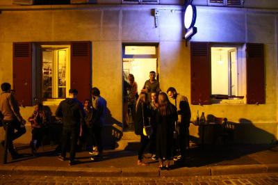 Bouteilles variées alignées sur une étagère en bois dans un bar avec une enseigne ’L'Astrolabe’ en arrière-plan.