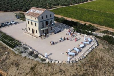 Personnes rassemblées devant une grande maison avec des tentes blanches, un brasero avec brochettes au premier plan.