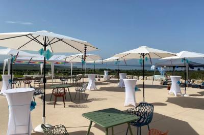 Personnes rassemblées devant une grande maison avec des tentes blanches, un brasero avec brochettes au premier plan.