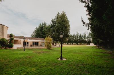 Portail en fer forgé noir et mur en pierre avec inscription ’Les Charbenes du Donelay, Domaine de réception’.