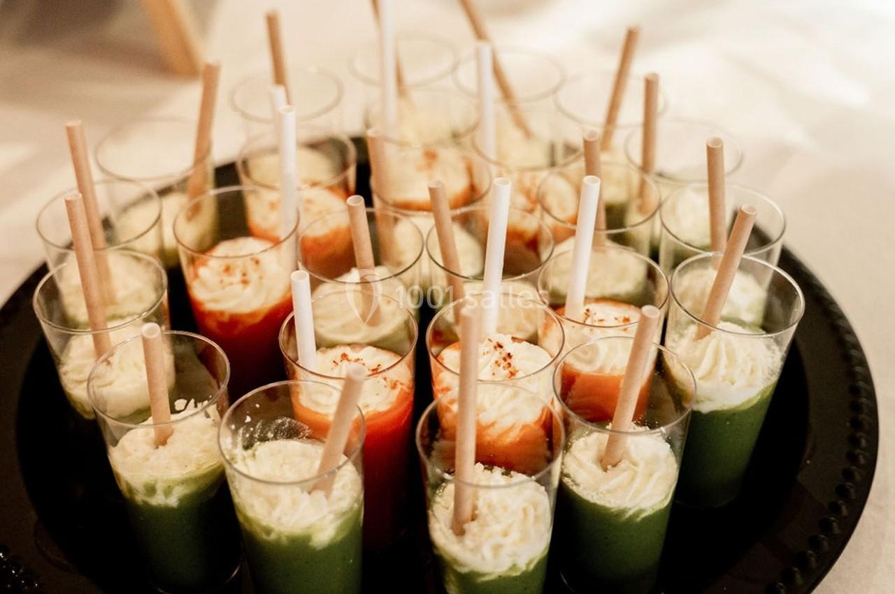 Plateau de verrines colorées contenant des préparations vertes et rouges, garnies de crème et de pailles.