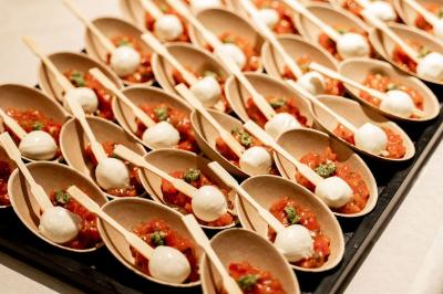 Cuillères en bois garnies de tomates, mozzarella et pesto, présentées sur un plateau pour un service individuel.