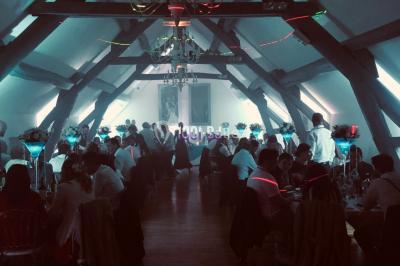 Salle de réception décorée avec des tables rondes éclairées en bleu, nappes blanches et bougies allumées.