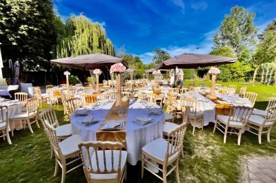 Chaises longues et tables disposées sur une pelouse, entourées de bâtiments colorés et éclairées par des guirlandes…