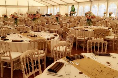 Chaises longues et tables disposées sur une pelouse, entourées de bâtiments colorés et éclairées par des guirlandes…