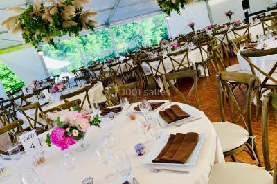 Chaises longues et tables disposées sur une pelouse, entourées de bâtiments colorés et éclairées par des guirlandes…