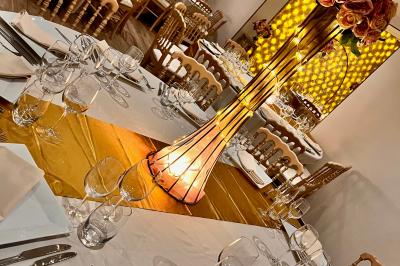 Chaises longues et tables disposées sur une pelouse, entourées de bâtiments colorés et éclairées par des guirlandes…