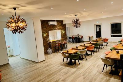 Chaises longues et tables disposées sur une pelouse, entourées de bâtiments colorés et éclairées par des guirlandes…