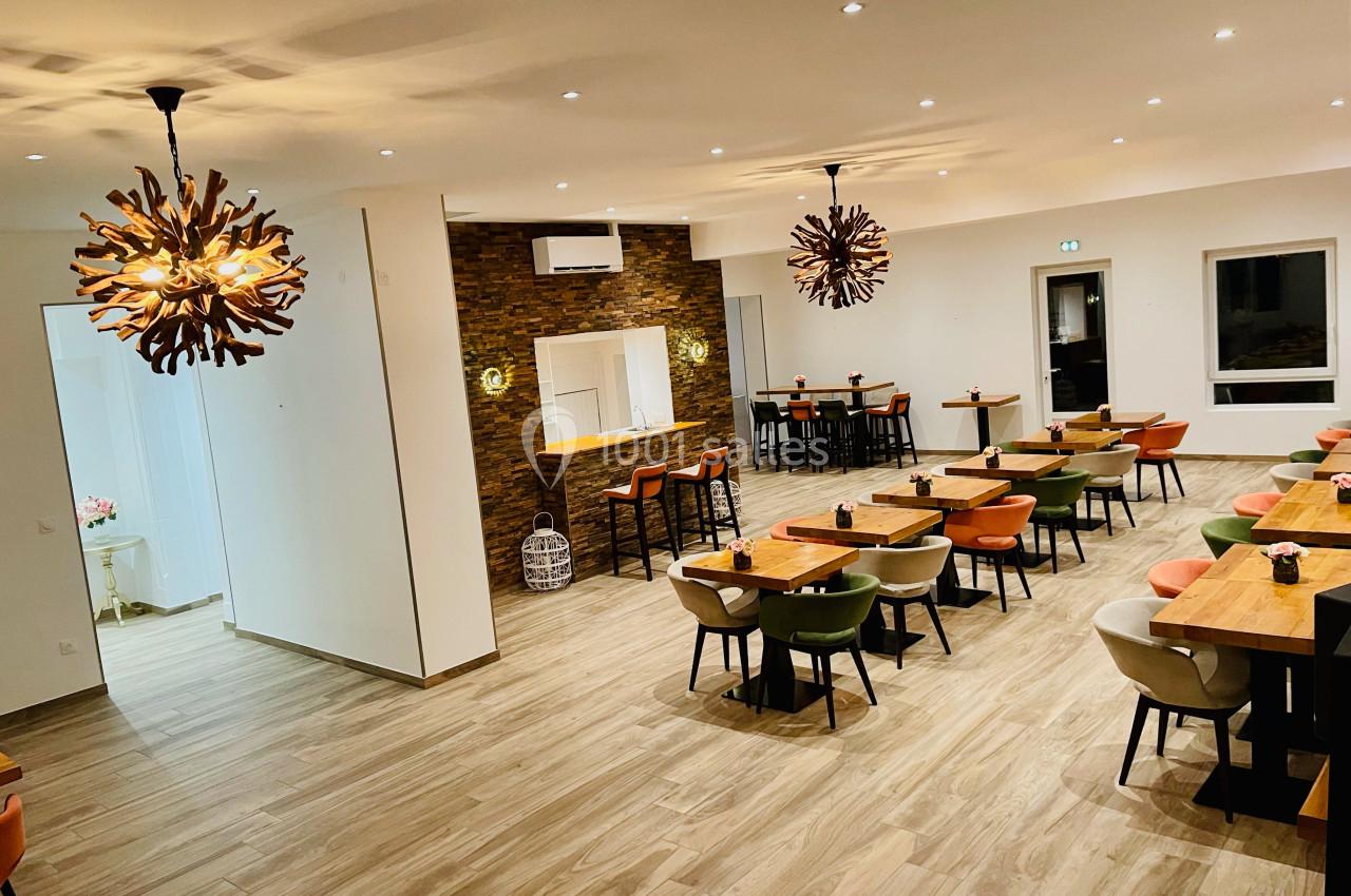 Salle de restaurant moderne avec tables en bois, chaises colorées et luminaires design en bois suspendus.
