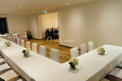 Chaises longues et tables disposées sur une pelouse, entourées de bâtiments colorés et éclairées par des guirlandes…