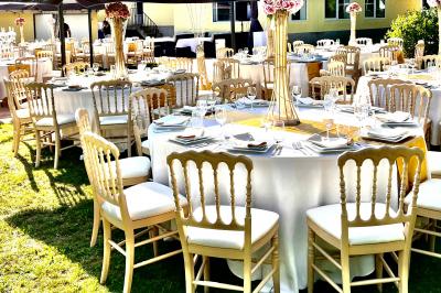 Chaises longues et tables disposées sur une pelouse, entourées de bâtiments colorés et éclairées par des guirlandes…