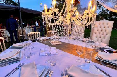 Chaises longues et tables disposées sur une pelouse, entourées de bâtiments colorés et éclairées par des guirlandes…