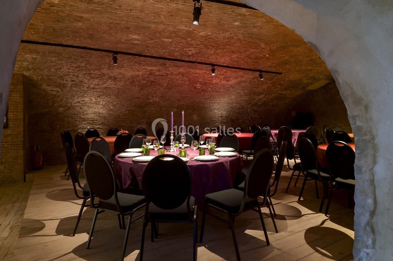 Location salle Bruxelles (Bruxelles-Capitale) - Théâtre de la Samaritaine #2 Salle voûtée avec des tables rondes dressées pour un repas, éclairée par des bougies et des lumières tamisées.