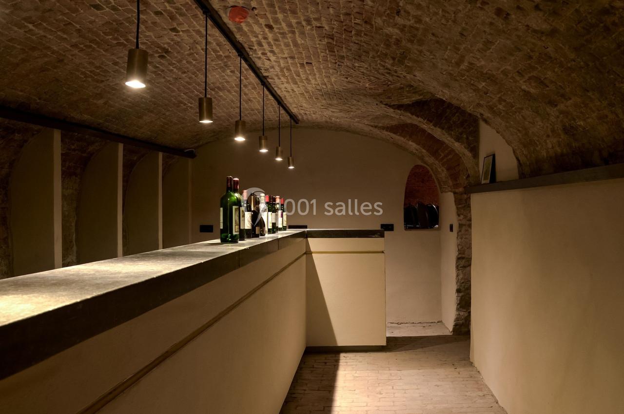 Location salle Bruxelles (Bruxelles-Capitale) - Théâtre de la Samaritaine #6 Cave voûtée en briques avec un comptoir éclairé et des bouteilles disposées dessus.