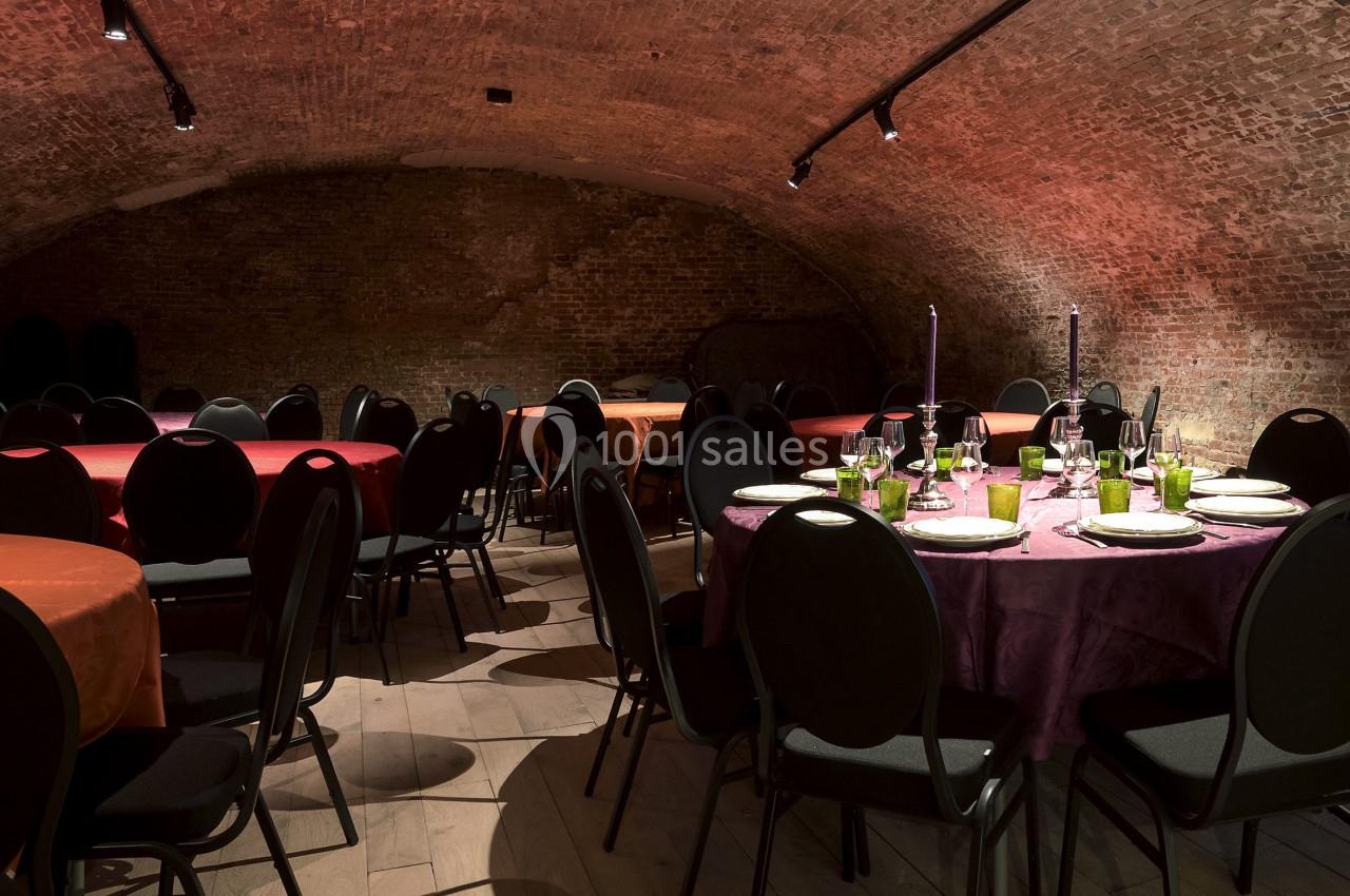 Location salle Bruxelles (Bruxelles-Capitale) - Théâtre de la Samaritaine #1 Salle voûtée en briques avec tables rondes dressées, nappes colorées et chaises noires, éclairée par des spots.