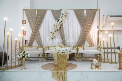 Arrangement floral blanc et rose sur une table dorée, avec un fond de rideaux roses et des décorations florales.