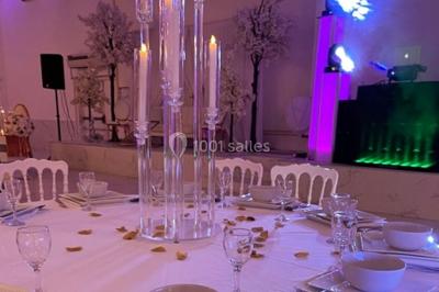 Arrangement floral blanc et rose sur une table dorée, avec un fond de rideaux roses et des décorations florales.
