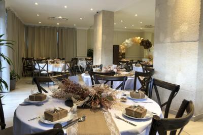 Salle décorée pour un événement, avec des tables rondes dressées, ornées de centres de table naturels et cadeaux.