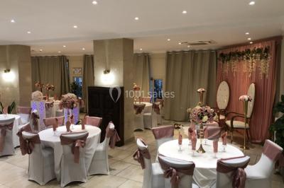 Salle décorée pour un événement, avec des tables rondes dressées, ornées de centres de table naturels et cadeaux.