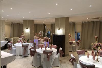 Salle décorée pour un événement, avec des tables rondes dressées, ornées de centres de table naturels et cadeaux.