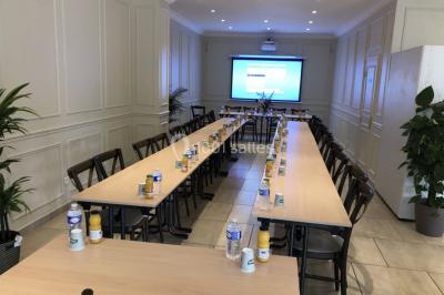 Salle décorée pour un événement, avec tables ornées de fleurs et colonnes blanches ajourées devant des rideaux beiges.