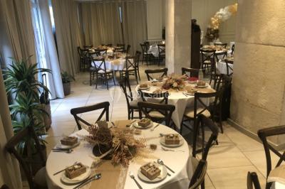 Salle décorée pour un événement, avec tables ornées de fleurs et colonnes blanches ajourées devant des rideaux beiges.