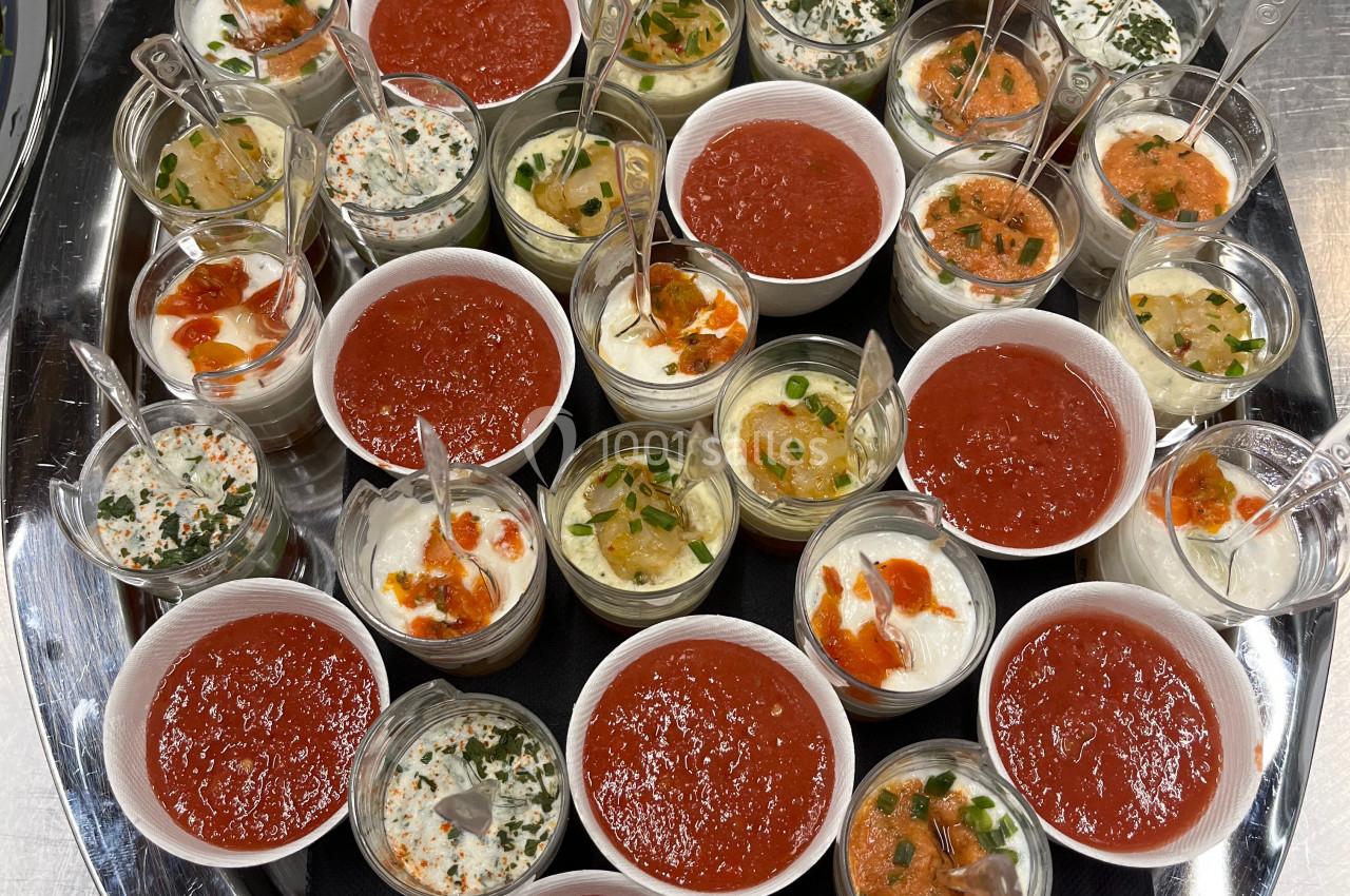 Plateau de verrines variées comprenant des préparations salées et sucrées, disposées sur une table en inox.