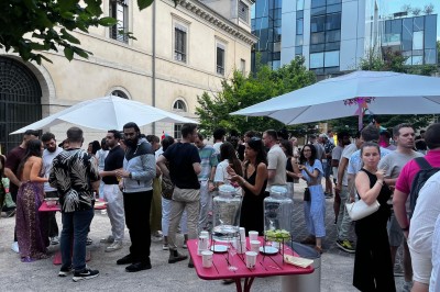 Bâtiment ancien avec façade beige, horloge centrale et dôme, entouré de végétation sous un ciel bleu.