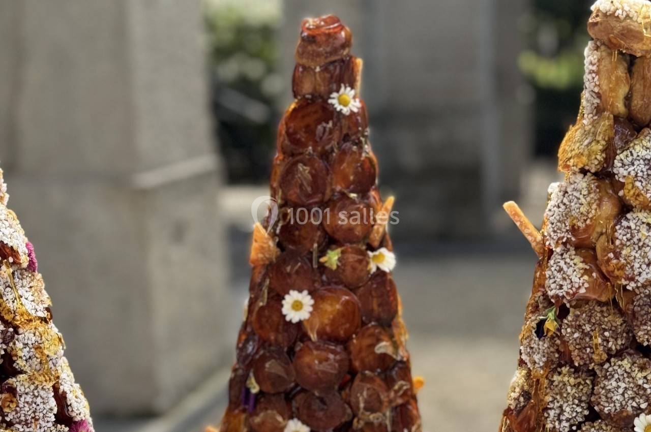 Trois croquembouches décorés de fleurs et de sucre, exposés en extérieur sous une lumière naturelle.