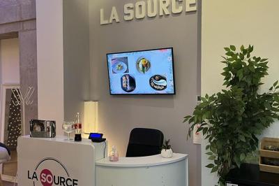 Groupe de personnes rassemblées autour de tables sous des parasols dans une cour extérieure avec végétation.