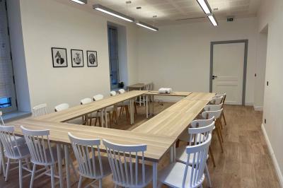 Groupe de personnes rassemblées autour de tables sous des parasols dans une cour extérieure avec végétation.