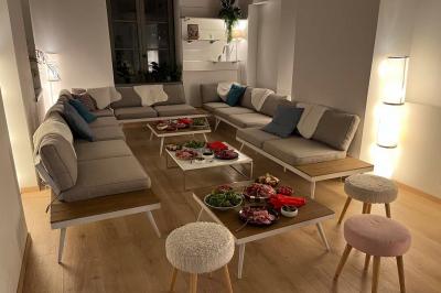 Groupe de personnes rassemblées autour de tables sous des parasols dans une cour extérieure avec végétation.