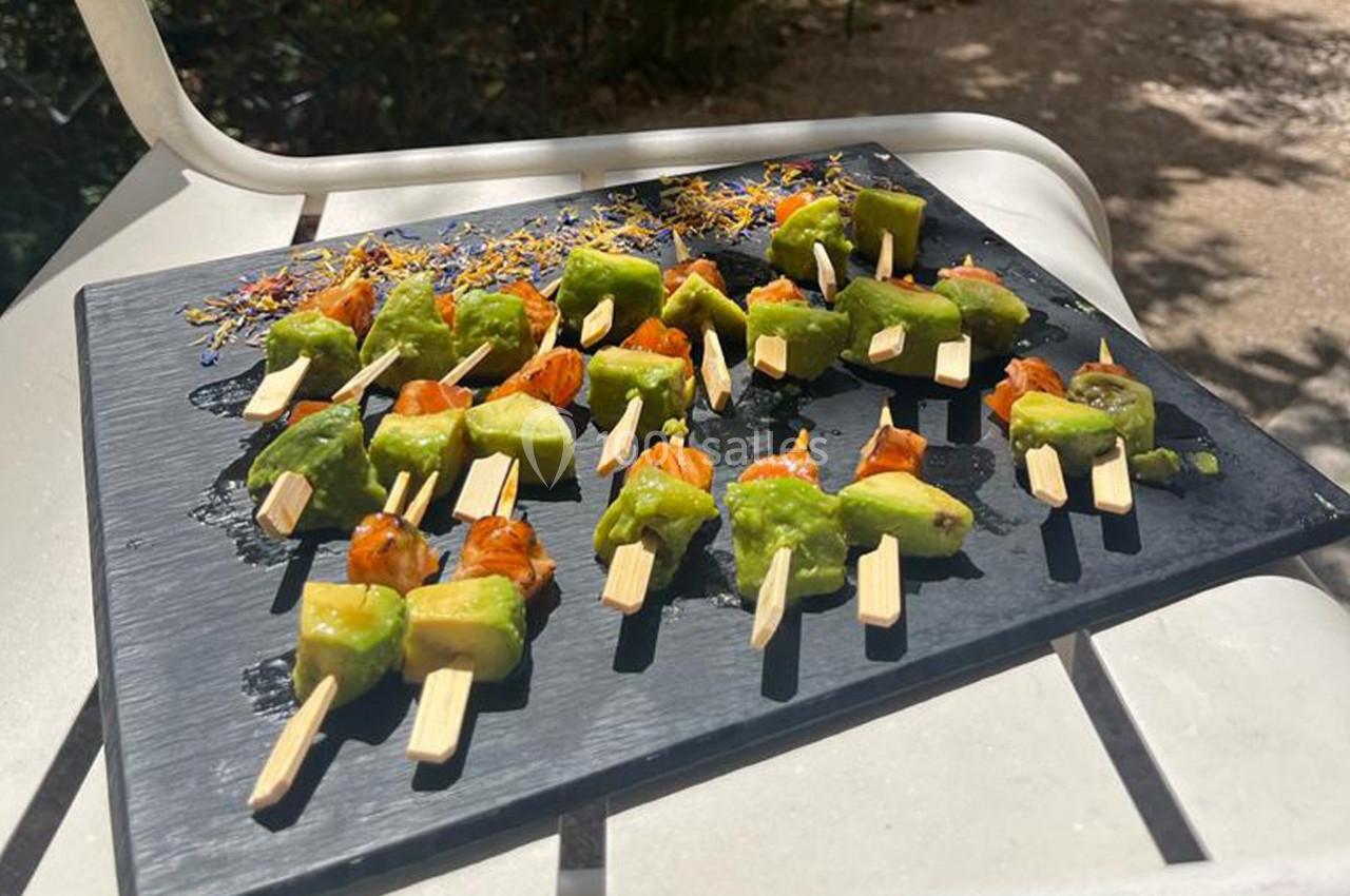 Brochettes apéritives avec morceaux d'avocat et tomates cerises, présentées sur une ardoise noire en extérieur.