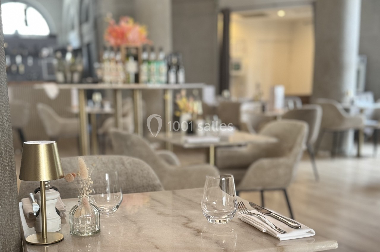 Table élégamment dressée dans un restaurant lumineux avec des chaises confortables et un décor raffiné en arrière-plan.