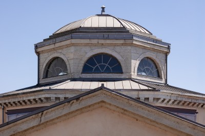 Dôme octogonal avec fenêtres cintrées et toit en métal, surmontant un bâtiment à façade triangulaire.