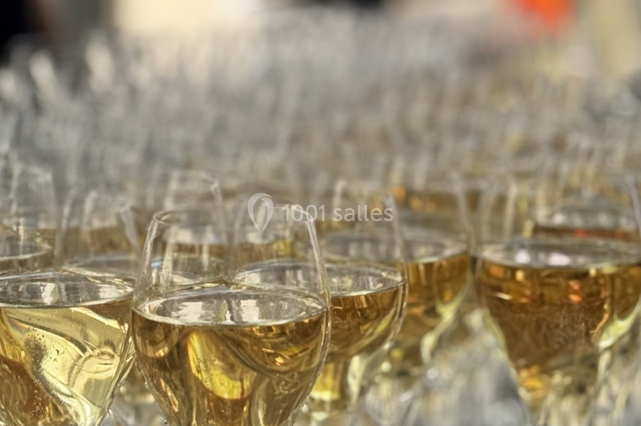 Rangée de verres remplis de vin blanc pétillant disposés sur une table lors d'un événement.