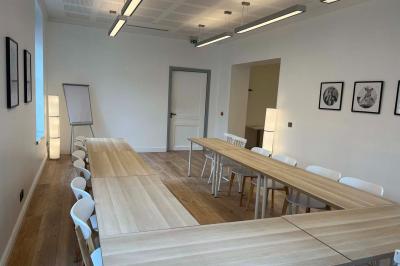 Groupe de personnes rassemblées autour de tables sous des parasols dans une cour extérieure avec végétation.