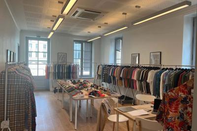 Groupe de personnes rassemblées autour de tables sous des parasols dans une cour extérieure avec végétation.