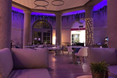 Groupe de personnes rassemblées autour de tables sous des parasols dans une cour extérieure avec végétation.