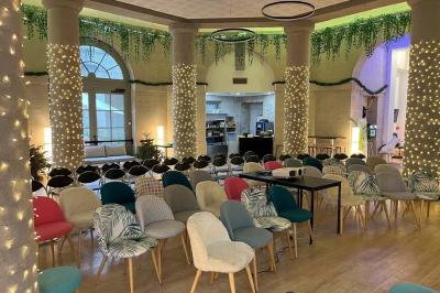 Groupe de personnes rassemblées autour de tables sous des parasols dans une cour extérieure avec végétation.