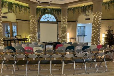 Groupe de personnes rassemblées autour de tables sous des parasols dans une cour extérieure avec végétation.