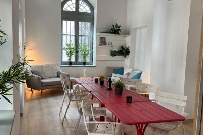 Groupe de personnes rassemblées autour de tables sous des parasols dans une cour extérieure avec végétation.