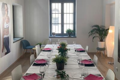 Groupe de personnes rassemblées autour de tables sous des parasols dans une cour extérieure avec végétation.