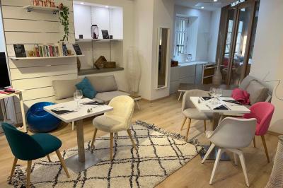Groupe de personnes rassemblées autour de tables sous des parasols dans une cour extérieure avec végétation.