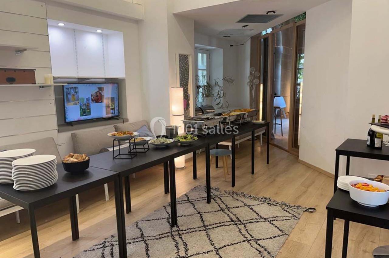 Buffet installé dans une pièce lumineuse avec des tables noires, des plats variés et une décoration sobre.