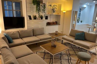 Groupe de personnes rassemblées autour de tables sous des parasols dans une cour extérieure avec végétation.