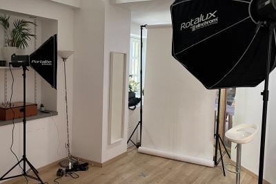 Groupe de personnes rassemblées autour de tables sous des parasols dans une cour extérieure avec végétation.