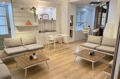 Groupe de personnes rassemblées autour de tables sous des parasols dans une cour extérieure avec végétation.