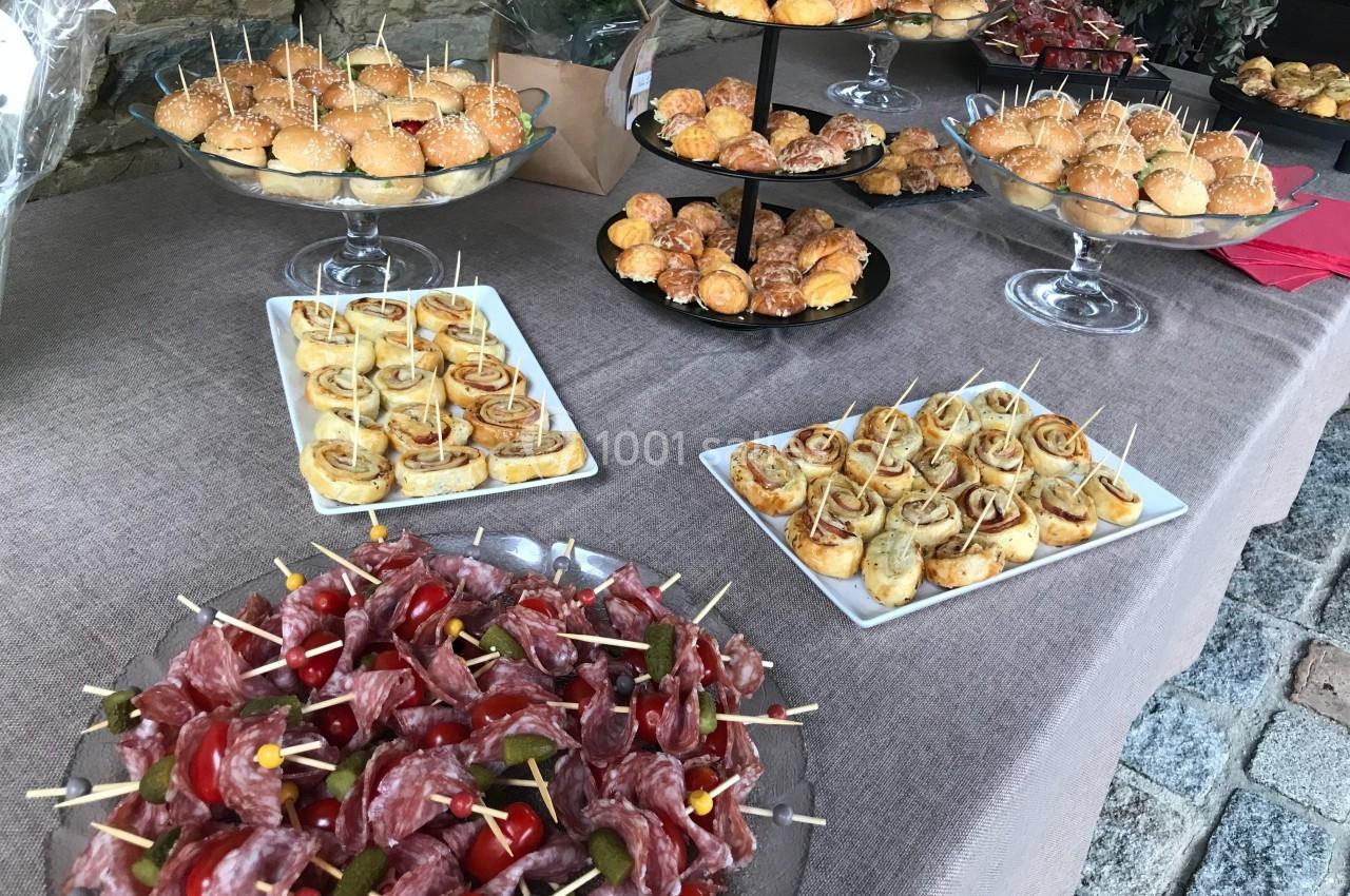 Plateau de buffet avec mini-sandwichs, feuilletés, roulés apéritifs et brochettes de charcuterie sur une nappe beige.