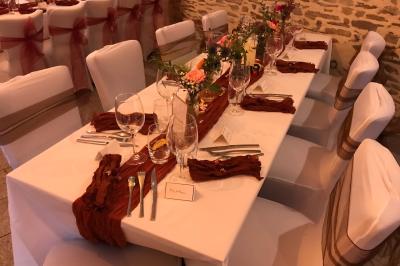 Une femme en robe de mariée est assise sur un tapis dans un jardin, tenant un bouquet de fleurs séchées.